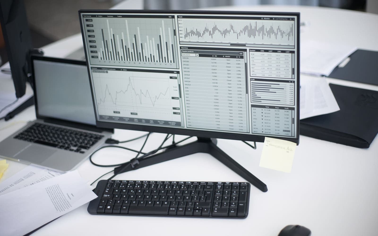 A desk workspace with a monitor showing analytics charts next to a laptop.