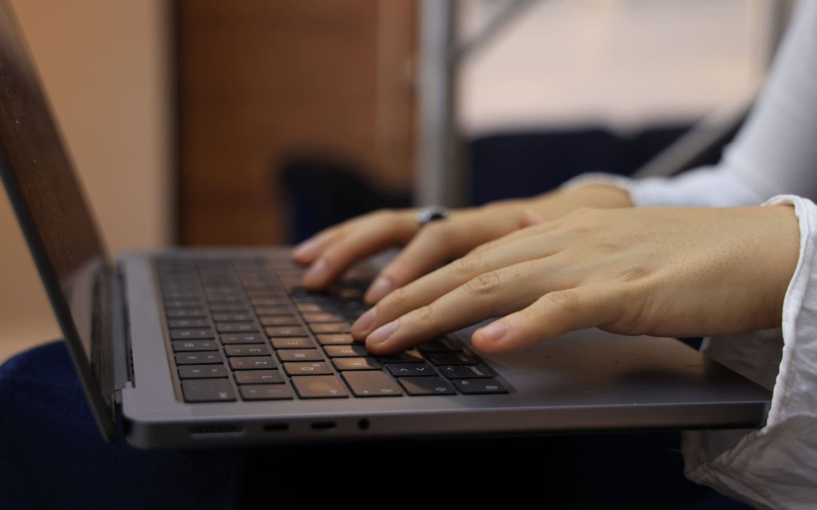 Close-up of a person's hands typing on a laptop keyboard.
